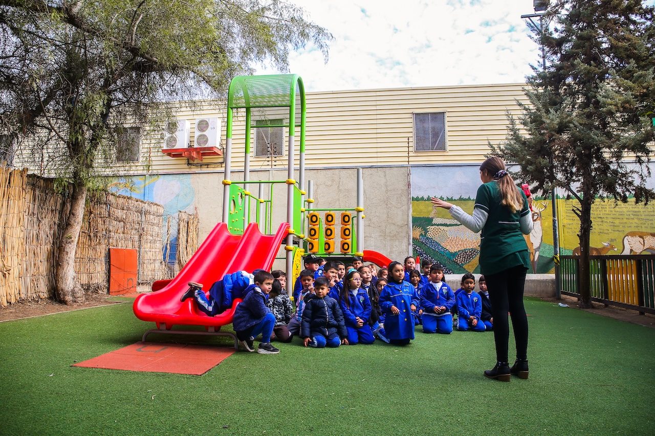 Educadora con párvulos en el patio de juegos del Colegio Mirador